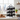 Black metal wine rack holding bottles on a kitchen counter with a cityscape view.